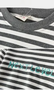 Detail of Next Level letter embroidery and striped cotton fabric on kids sweatshirt
