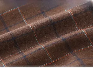 Close-up of brown checkered wool fabric with blue and orange plaid pattern details
