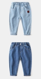 Detail of kids jeans showing elastic waistbands and a red patch on light blue denim