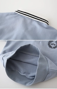 Detailed close-up of light blue polo collar with black stripes and brand embroidery