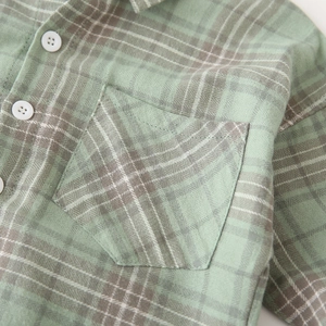 Detail of green and brown plaid cotton fabric with front pocket and white button