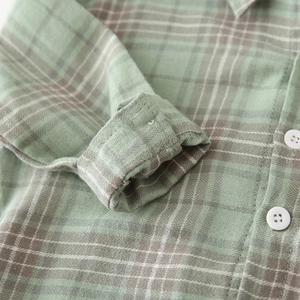 Detail of sage green and brown plaid cotton shirt showing sleeve cuffs and white buttons