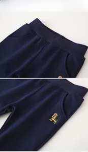 Detail of dark blue cotton kids pants with elastic waist and colorful tiger embroidery