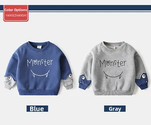 Detail view of cartoon monster sweaters for boys in blue and grey with sleeve eye decor