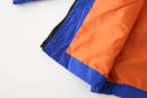 Detailed close-up of blue windbreaker fabric with orange lining and black zipper detail
