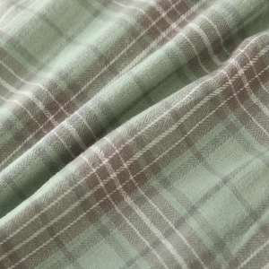 Detailed macro view of soft green and grey plaid cotton fabric for boys' shirts