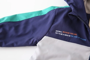 Close-up of color-block hooded jacket with windproof fabric and chest typography