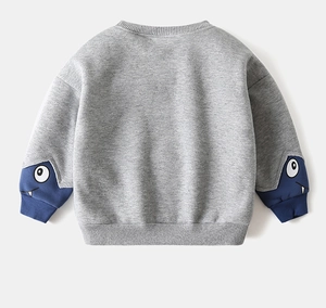Detail of grey kid's sweatshirt featuring cartoon monster embroidery on sleeve cuffs