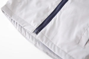 Detail of high-quality zipper closure and neat stitching on light gray windbreaker jacket