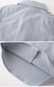 Detail of light blue boys' long-sleeve shirt showing turnover collar and wooden buttons