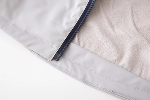 Close-up of kids' winter jacket featuring warm gray fleece lining and durable blue zipper