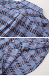 Detail view of blue plaid kids shirt showing flannel texture, stitching and curved hem