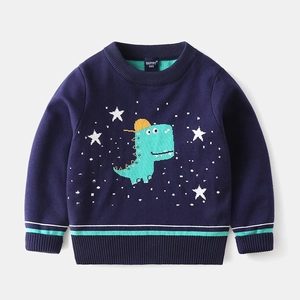 Detail of knit sweater showing cartoon green dinosaur pattern with yellow hat on navy base