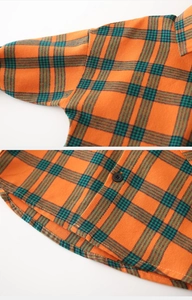 Détail d'une chemise à carreaux orange et vert montrant le bouton et la texture