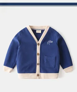 Detail of navy knit cardigan for boys with dinosaur embroidery and brown wooden buttons