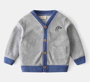 Detail of grey knitted cardigan showing blue trim and dinosaur embroidery with wood buttons