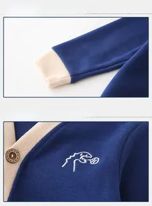 Detail of baby cardigan featuring dinosaur embroidery and contrast ribbed cuffs on navy blue