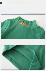 Detail of green turtleneck kid sweater featuring orange embroidery and knit texture