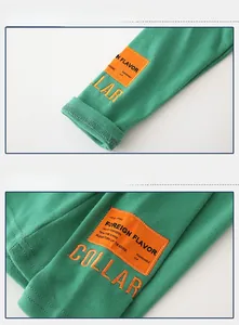 Detail of green cotton sweater showing orange patch embroidery and ribbed cuffs