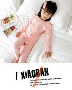 Vue détaillée du pyjama thermique rose clair pour enfants sur un lit blanc douillet