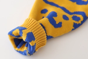 Detail of yellow knit sweater sleeve with blue jacquard pattern and ribbed cuff