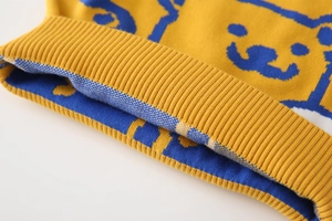 Close-up of knit fabric showing blue jacquard cartoon bear pattern and ribbed hem