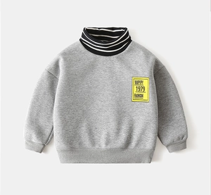 Close-up of boys' grey sweatshirt featuring striped high collar and yellow logo patch