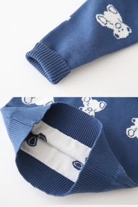 Close-up of ribbed cuffs and hem on blue knitted boy's sweater with white bear patterns