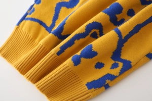 Detail of yellow knit sweater showing dense texture and ribbed cuffs for kids