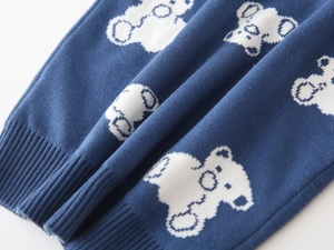 Detailed close-up of dark blue knit sweater cuff with white cartoon bear jacquard pattern