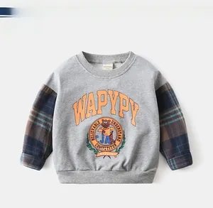 Detail of grey kids sweatshirt featuring checkered sleeves and cartoon bear graphic