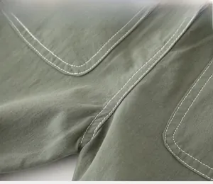 Detail of olive green cotton fabric with white contrast stitching on boy's shorts