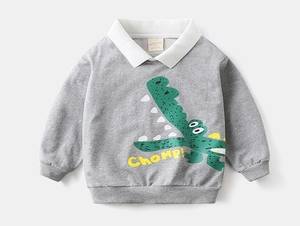 Detail of grey kids sweatshirt featuring green crocodile print and white collar accent