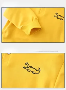 Detail of yellow knit polo sweatshirt featuring ribbed cuffs and black crocodile embroidery