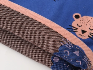 Close-up of kids knitted sweater showing animal jacquard pattern and ribbed cuffs