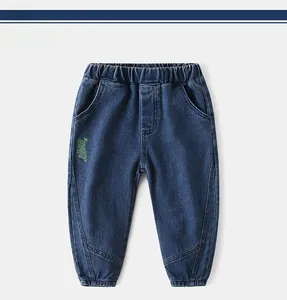 Detail of dark blue boys' denim joggers with elastic waist and green letter embroidery