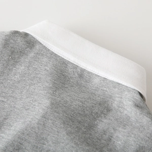 Close-up of grey mélange knit fabric with a white polo collar and neat stitching