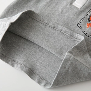 Macro detail of double-stitched hem on a grey cotton blend boys' polo t-shirt