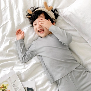 Pyjama thermique enfant gris clair avec bandeau renne en peluche sur literie blanche