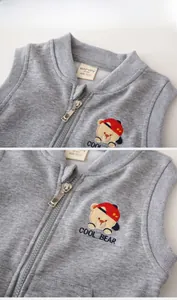 Gros plan du gilet gris en maille avec broderie d'ours et fermeture éclair fluide