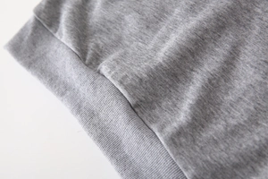 Vue macro détaillée de l'ourlet côtelé gris chiné et des coutures sur ce gilet pour enfant
