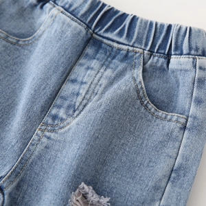 Détail de la taille élastique d'un jean bleu pour enfant avec tissu denim usé et poches
