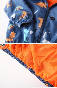 Close-up of kids' navy jacket with dinosaur prints and orange mesh lining detail