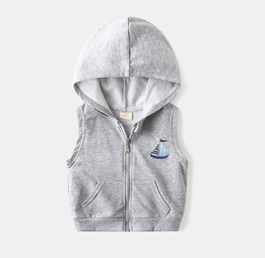 Gros plan d'un gilet gris à capuche pour enfant avec broderie de voilier et fermeture éclair