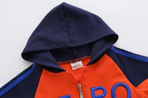 Detail der Kinderkapuzenjacke mit marineblauen und orangefarbenen Kontrasten und Stickerei