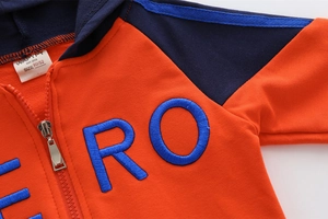 Detail eines Kinder-Hoodies mit orangefarbenem Stoff, blauem ERO-Stick und Reißverschluss