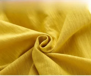 Gros plan sur la maille de coton flammé jaune montrant la texture douce et les fibres du tissu