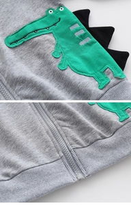 Dettaglio felpa grigia in cotone con cappuccio, ricamo dinosauro e punte decorative
