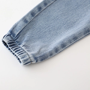 Vue macro détaillée du tissu denim bleu clair avec poignets élastiqués et coutures de qualité