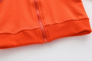 Detailansicht des orangefarbenen Hoodies mit robustem Reißverschluss und Rippbündchen